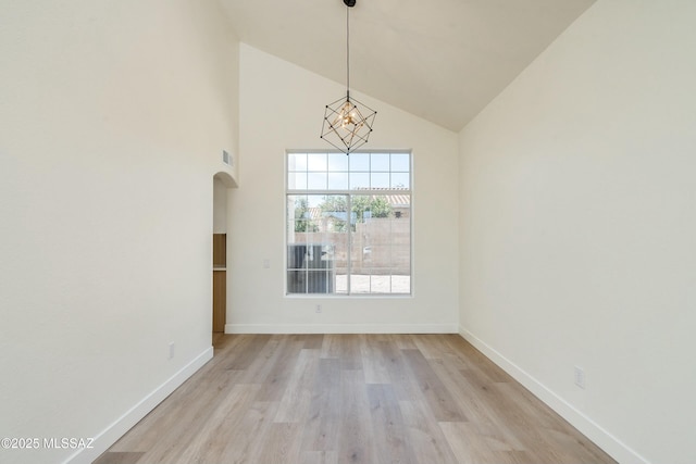 unfurnished dining area featuring high vaulted ceiling, light hardwood / wood-style flooring, and a notable chandelier