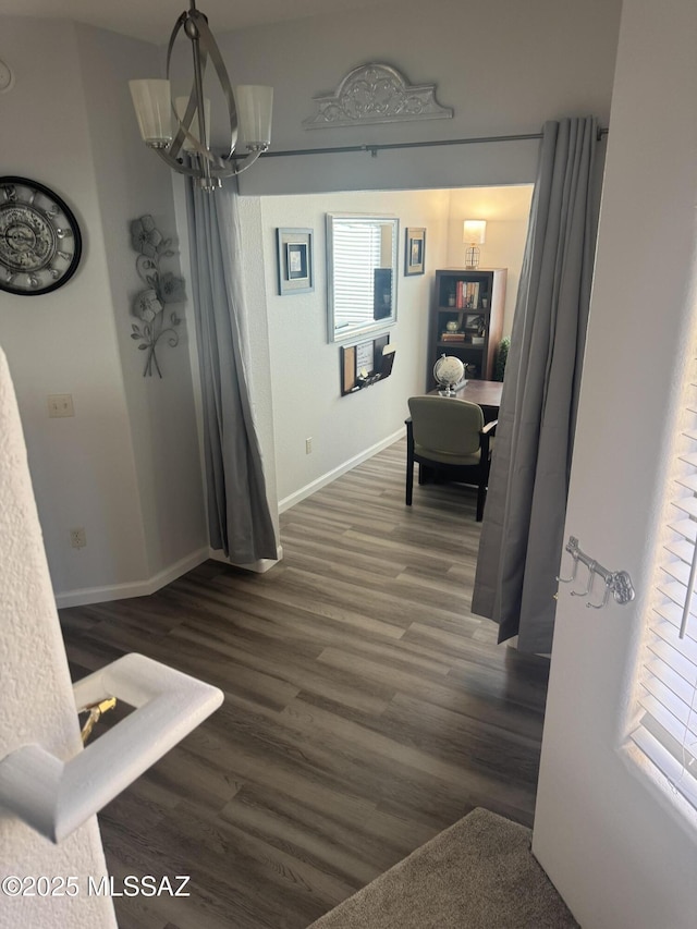 corridor with dark wood-type flooring and a chandelier