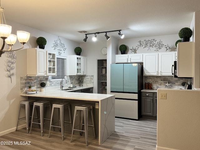 kitchen with a chandelier, a breakfast bar area, a peninsula, freestanding refrigerator, and a sink