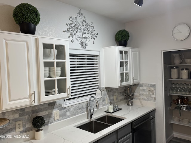 kitchen with tasteful backsplash, light stone countertops, sink, and white cabinets