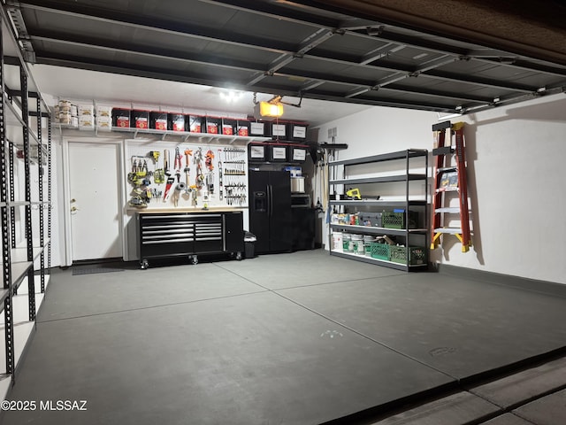 garage with black fridge with ice dispenser and a workshop area