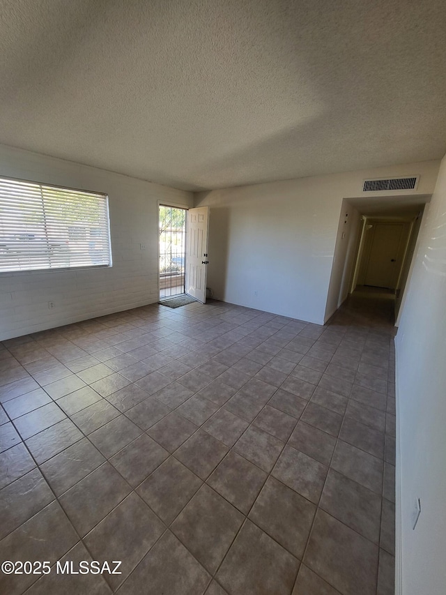 spare room featuring tile patterned flooring and a textured ceiling