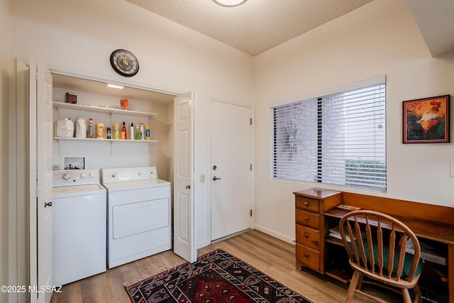 laundry area featuring washing machine and dryer, a textured ceiling, and light wood-type flooring