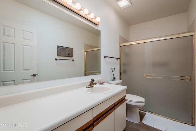 bathroom featuring vanity, wood-type flooring, an enclosed shower, and toilet