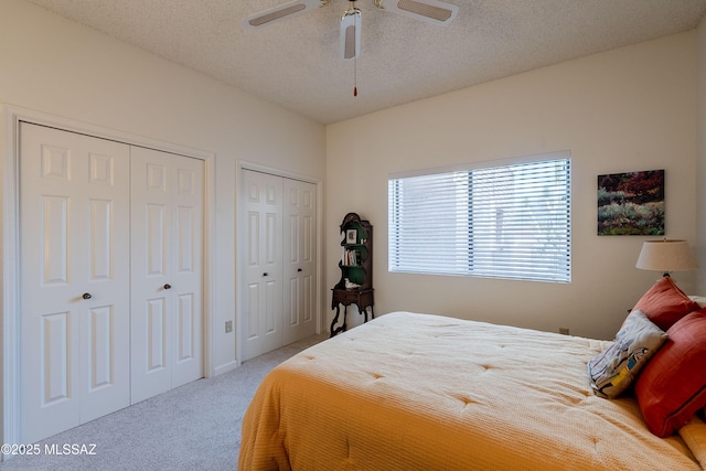 carpeted bedroom featuring multiple closets, ceiling fan, and a textured ceiling