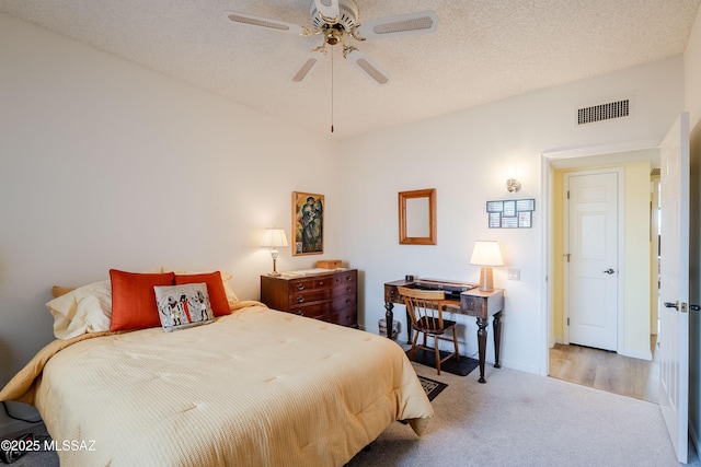 bedroom featuring ceiling fan, light carpet, and a textured ceiling