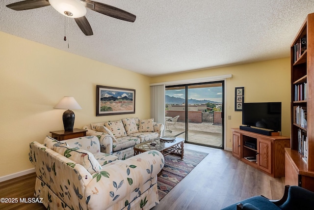 living room with dark wood-type flooring, ceiling fan, and a textured ceiling