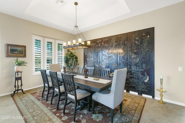 tiled dining space featuring an inviting chandelier and a tray ceiling