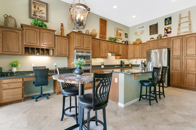 kitchen with a kitchen island with sink, built in desk, a kitchen bar, and a towering ceiling