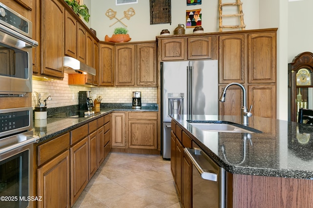 kitchen featuring dark stone countertops, appliances with stainless steel finishes, sink, and backsplash