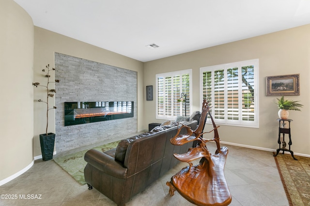living room with a stone fireplace and light tile patterned flooring