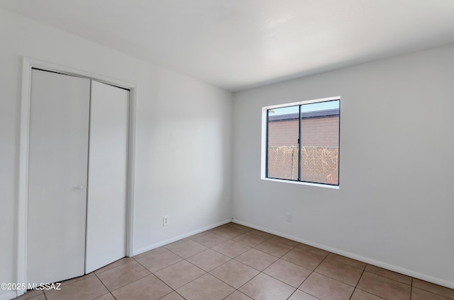 unfurnished bedroom with a closet and light tile patterned floors