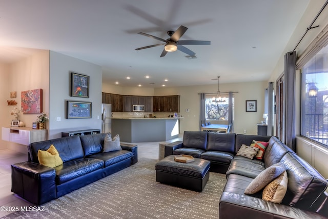 living room featuring ceiling fan with notable chandelier