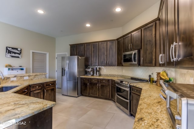 kitchen with light stone counters, dark brown cabinetry, and appliances with stainless steel finishes