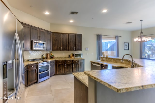 kitchen with hanging light fixtures, dark brown cabinets, sink, and appliances with stainless steel finishes