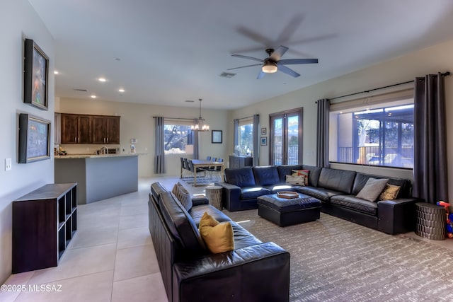 tiled living room with ceiling fan with notable chandelier