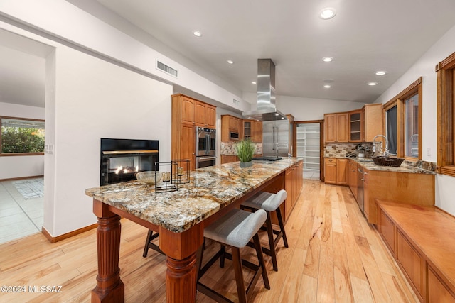 kitchen featuring visible vents, island range hood, backsplash, and a breakfast bar area