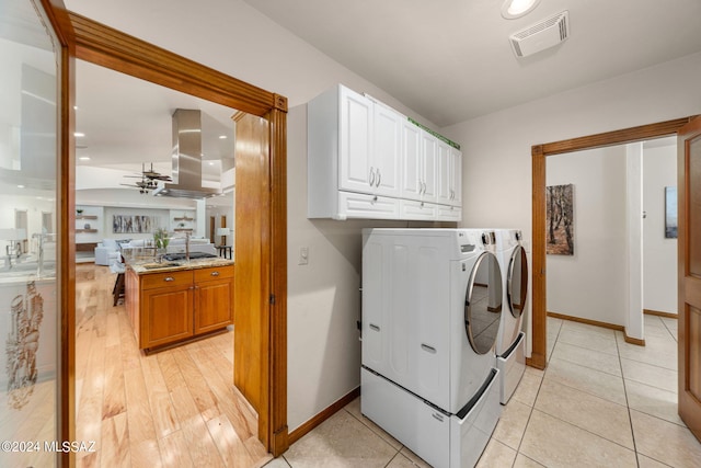 laundry area with visible vents, baseboards, washer and dryer, light wood-type flooring, and cabinet space