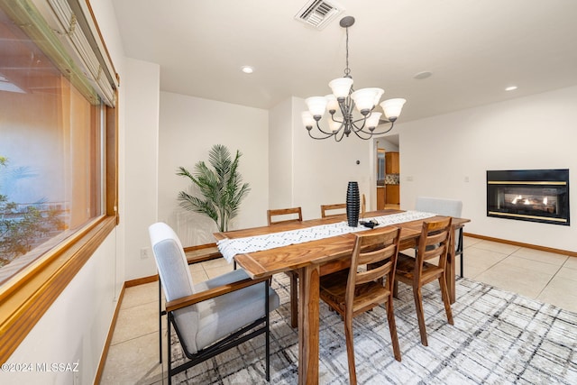 dining area featuring a glass covered fireplace, visible vents, a notable chandelier, and light tile patterned floors