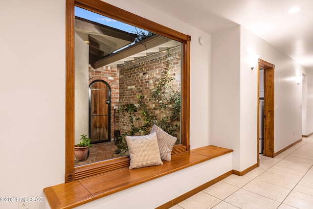 corridor featuring light tile patterned flooring and baseboards