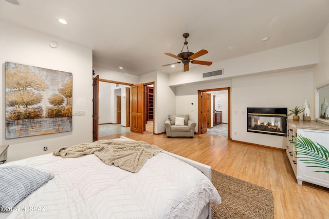 bedroom with recessed lighting, visible vents, light wood-style flooring, ceiling fan, and a multi sided fireplace