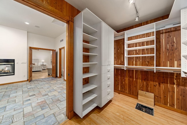 walk in closet with visible vents and a multi sided fireplace