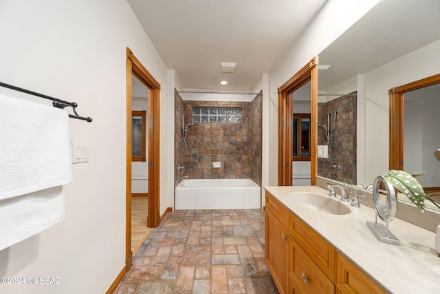 full bath with stone finish flooring, shower / tub combination, vanity, and baseboards