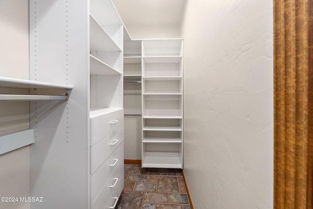 walk in closet with stone finish floor