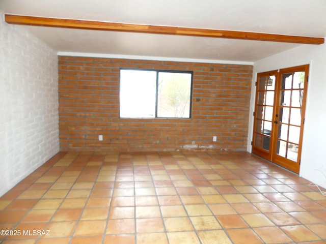 empty room with light tile patterned floors, beam ceiling, french doors, and brick wall