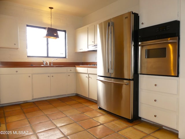 kitchen with pendant lighting, sink, white cabinets, and appliances with stainless steel finishes