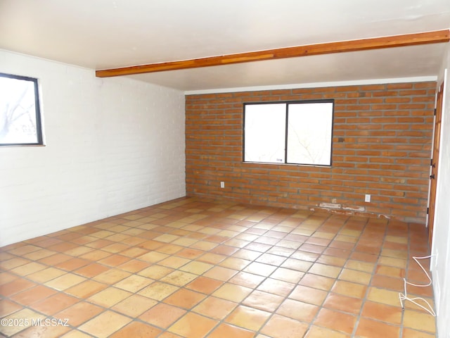 unfurnished room featuring beamed ceiling and brick wall