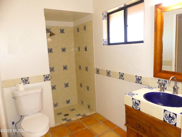 bathroom featuring vanity, tile patterned flooring, toilet, and tiled shower