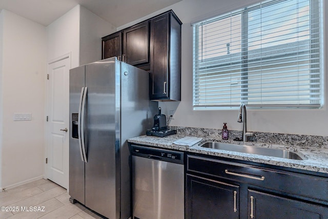 kitchen with light stone counters, sink, light tile patterned floors, and appliances with stainless steel finishes