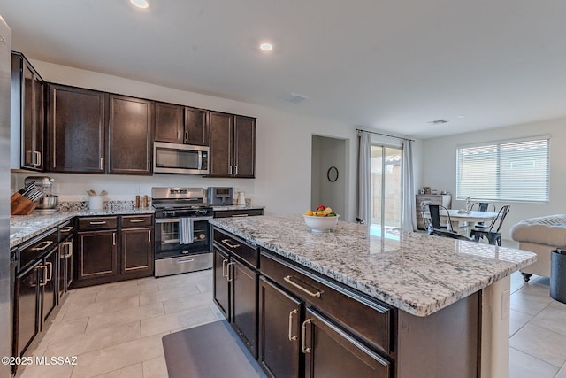 kitchen featuring dark brown cabinetry, appliances with stainless steel finishes, a kitchen island, and light tile patterned floors