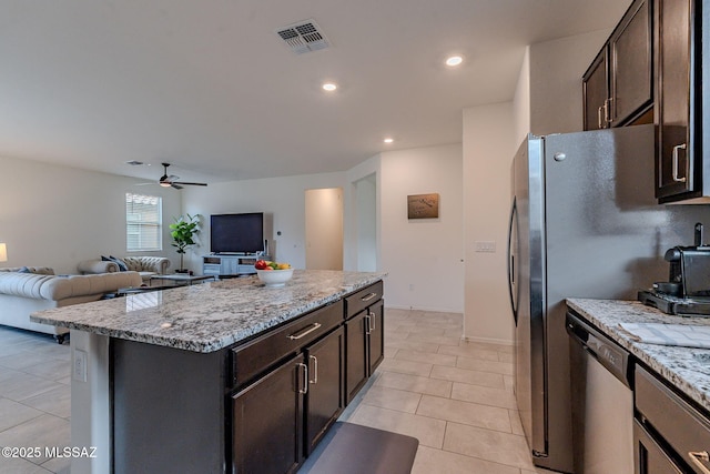 kitchen featuring light stone counters, light tile patterned floors, a kitchen island, ceiling fan, and stainless steel appliances