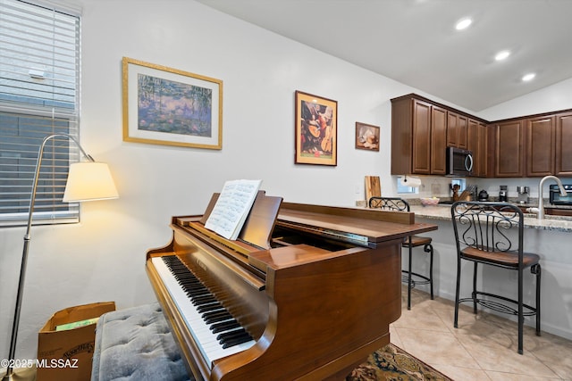 interior space featuring light tile patterned floors, vaulted ceiling, and sink