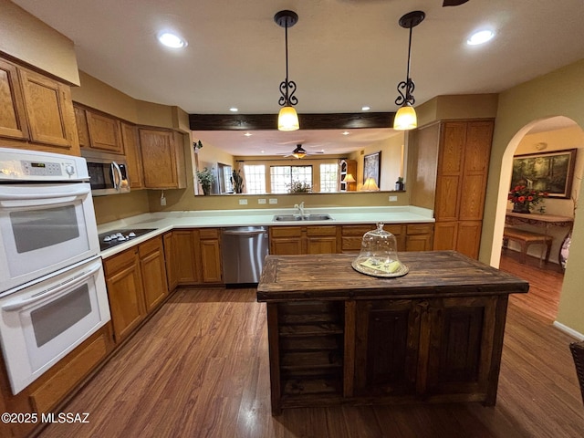 kitchen featuring pendant lighting, sink, wooden counters, kitchen peninsula, and stainless steel appliances