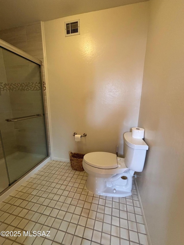 bathroom with an enclosed shower, tile patterned floors, and toilet