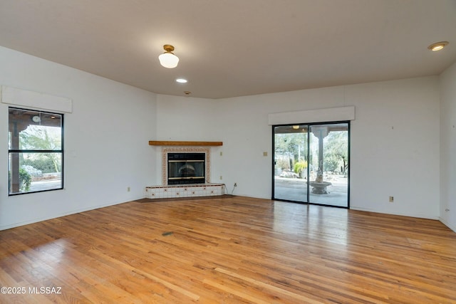 unfurnished living room featuring a tiled fireplace and light hardwood / wood-style floors