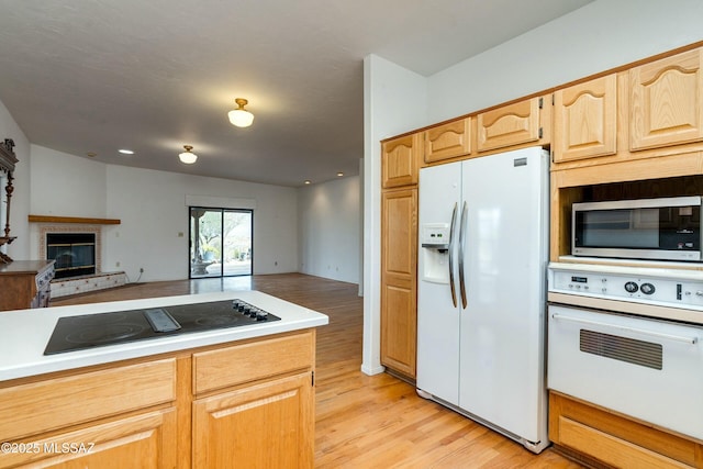 kitchen with light wood-type flooring, light brown cabinetry, and white appliances