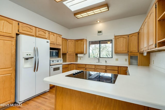 kitchen featuring sink, white appliances, kitchen peninsula, and light wood-type flooring