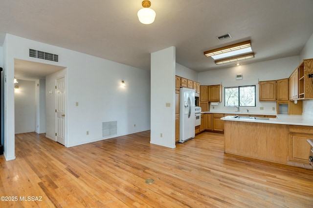 kitchen featuring sink, kitchen peninsula, white fridge with ice dispenser, light hardwood / wood-style floors, and stove