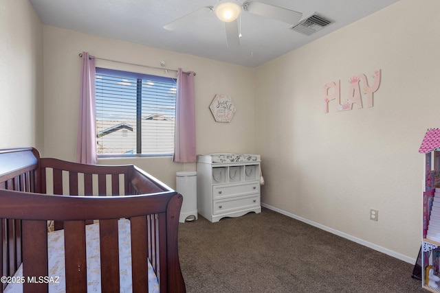 bedroom featuring a nursery area, ceiling fan, and dark colored carpet