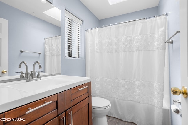 full bathroom featuring shower / bath combination with curtain, toilet, vanity, and a skylight