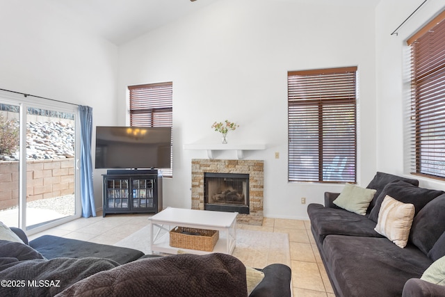 living room featuring a stone fireplace, high vaulted ceiling, and light tile patterned flooring