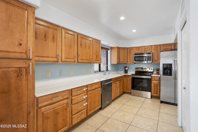 kitchen with appliances with stainless steel finishes, light stone countertops, sink, and light tile patterned floors