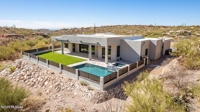 rear view of property featuring a patio area and an in ground hot tub