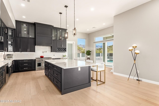 kitchen featuring pendant lighting, double oven range, a kitchen island, a kitchen bar, and light wood-type flooring