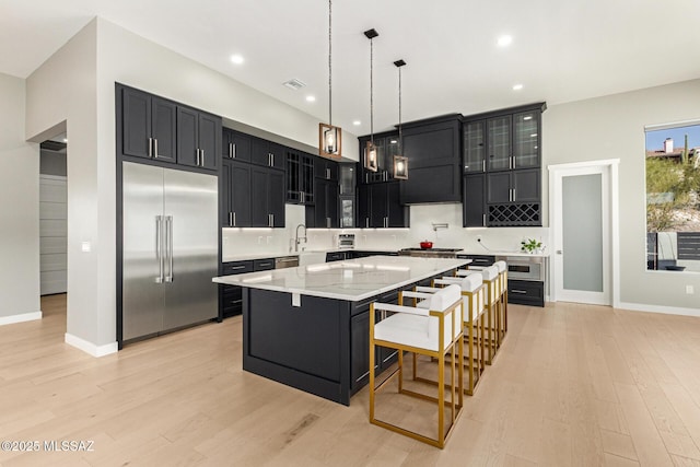 kitchen with a breakfast bar, light stone counters, light wood-type flooring, appliances with stainless steel finishes, and a kitchen island