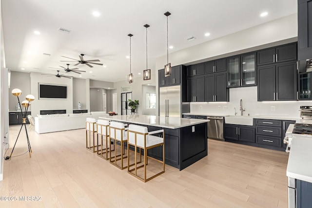 kitchen featuring sink, a breakfast bar area, hanging light fixtures, a kitchen island, and stainless steel appliances